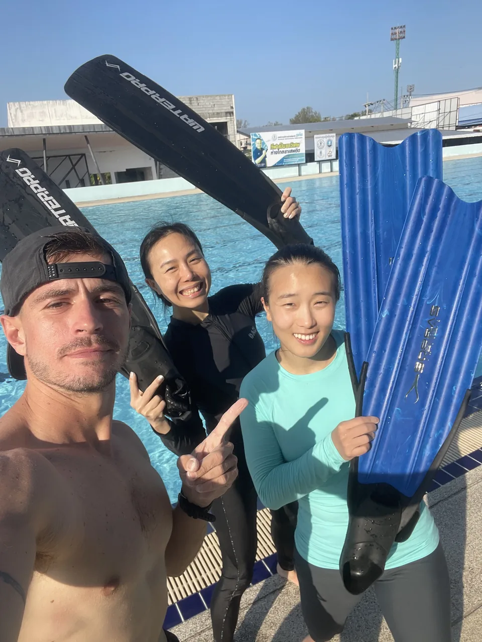 Freediving students holding fins beside a swimming pool