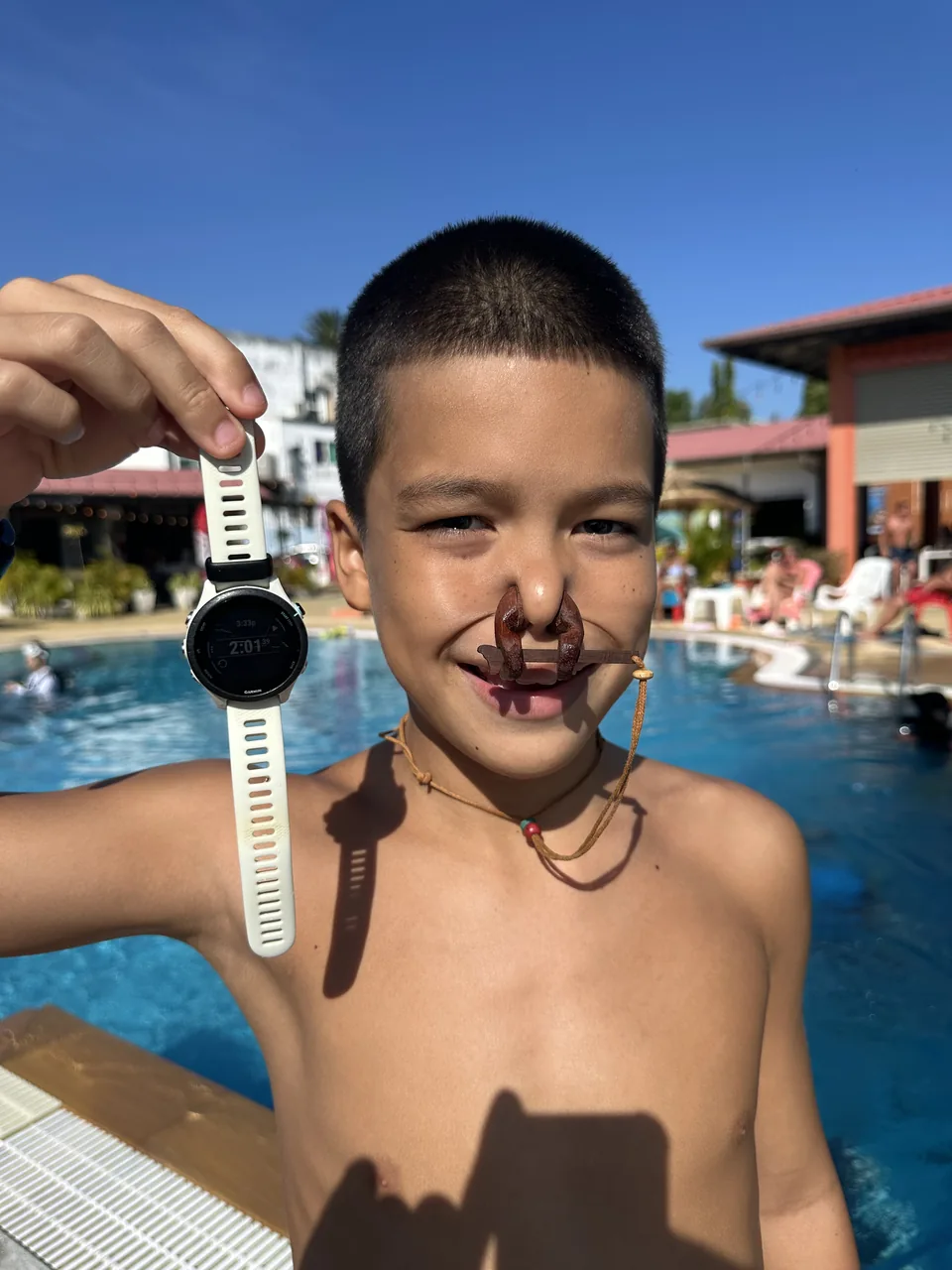 A young freediving student holding a dive watch beside the pool