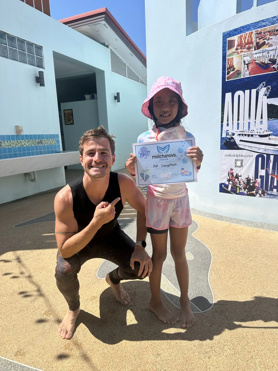 A child holding a junior freediving certificate beside an instructor