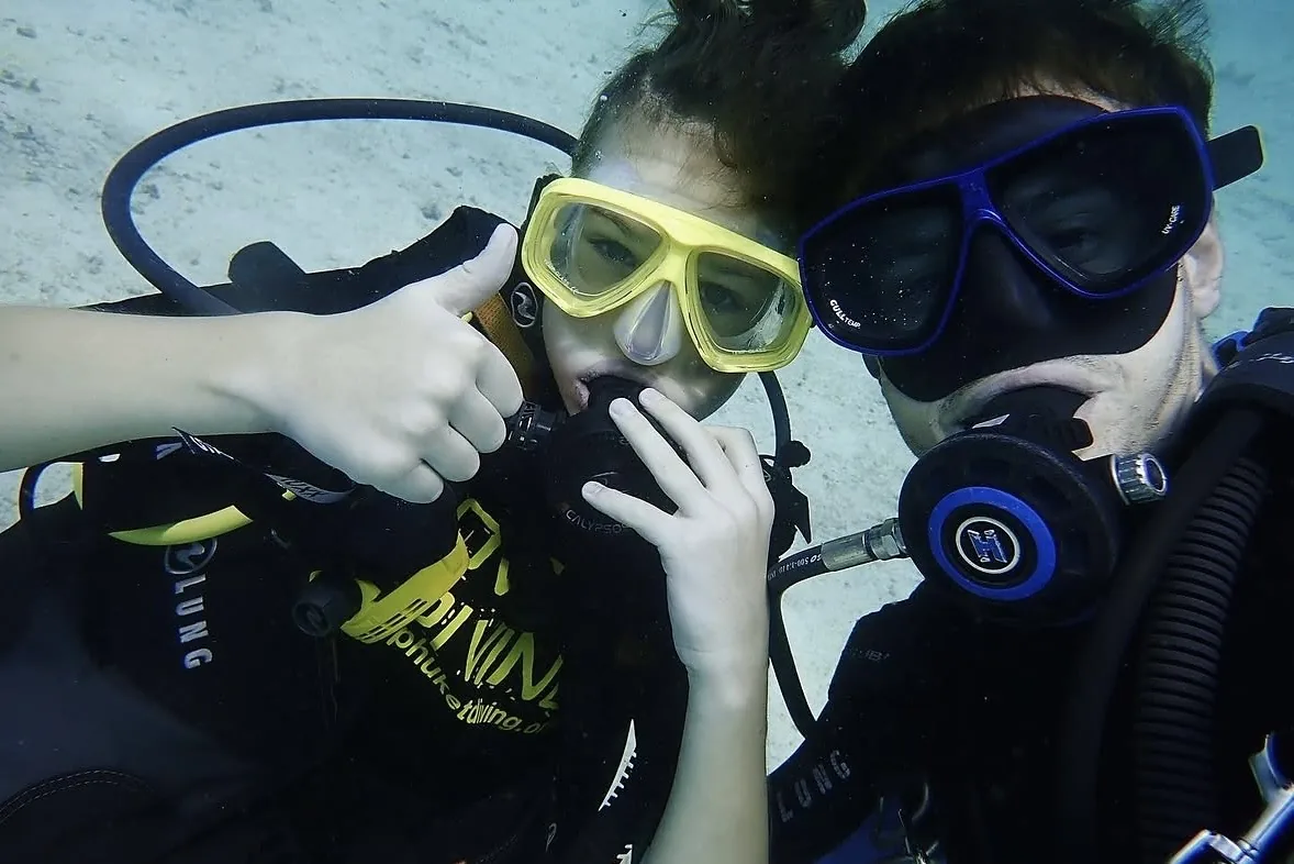 A young scuba diver and instructor underwater wearing masks and regulators