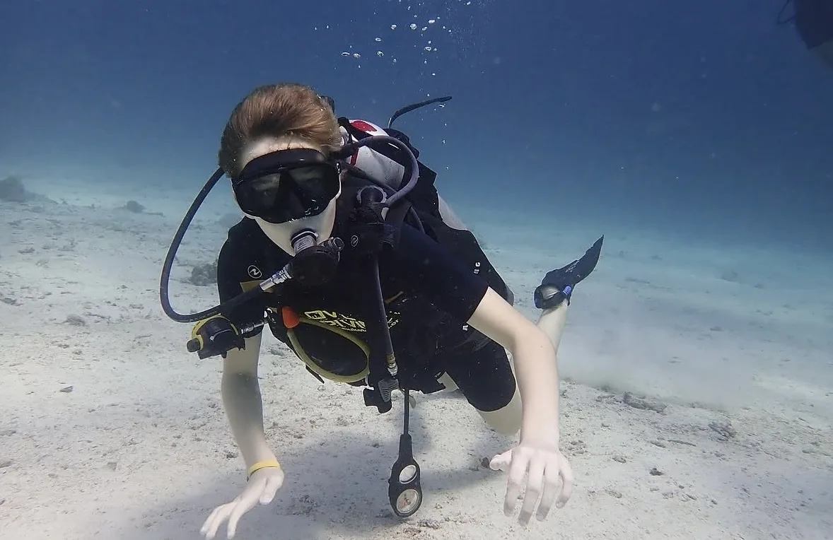 A young scuba diver exploring above a sandy seabed