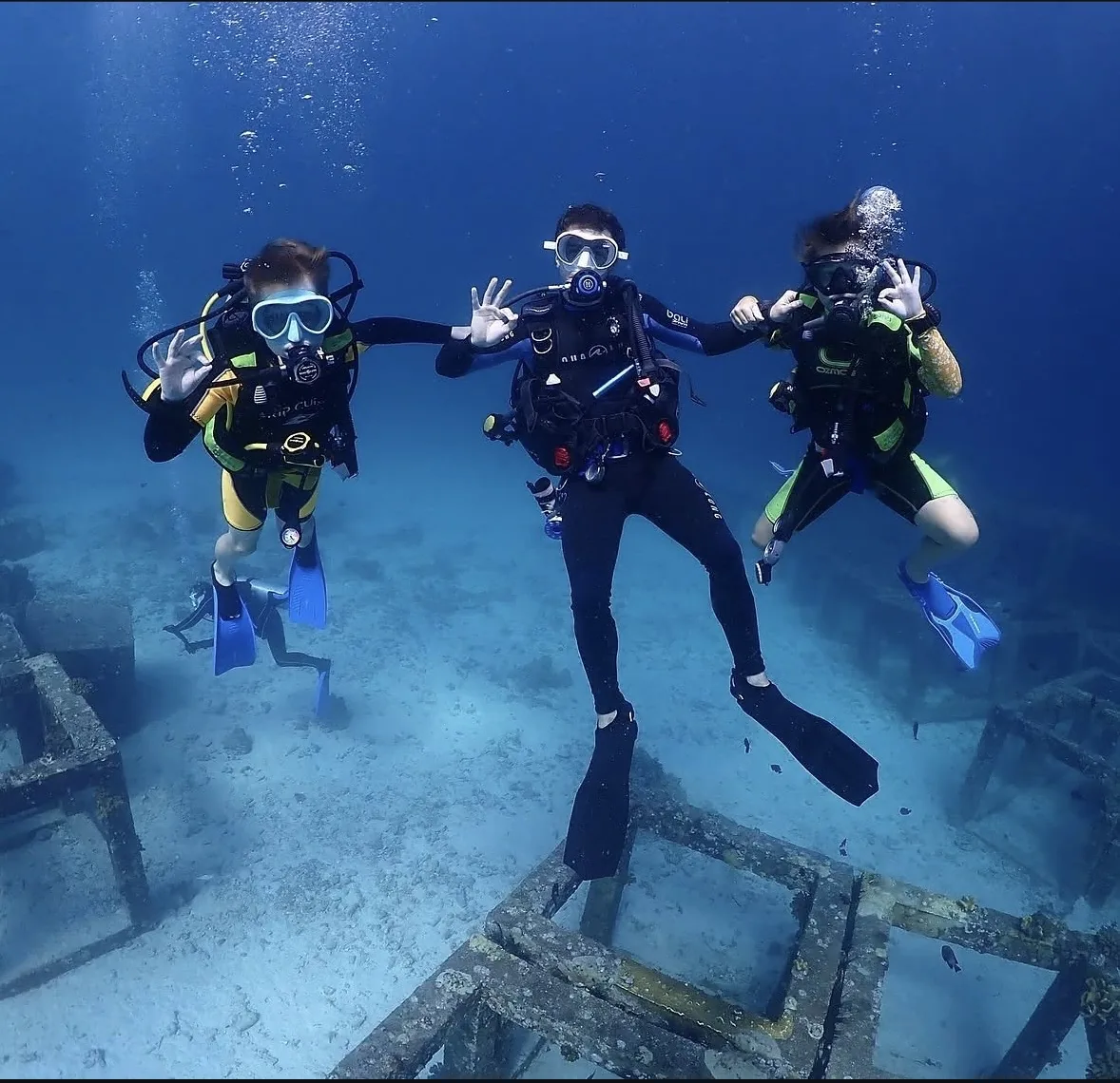 An instructor scuba diving underwater between two children