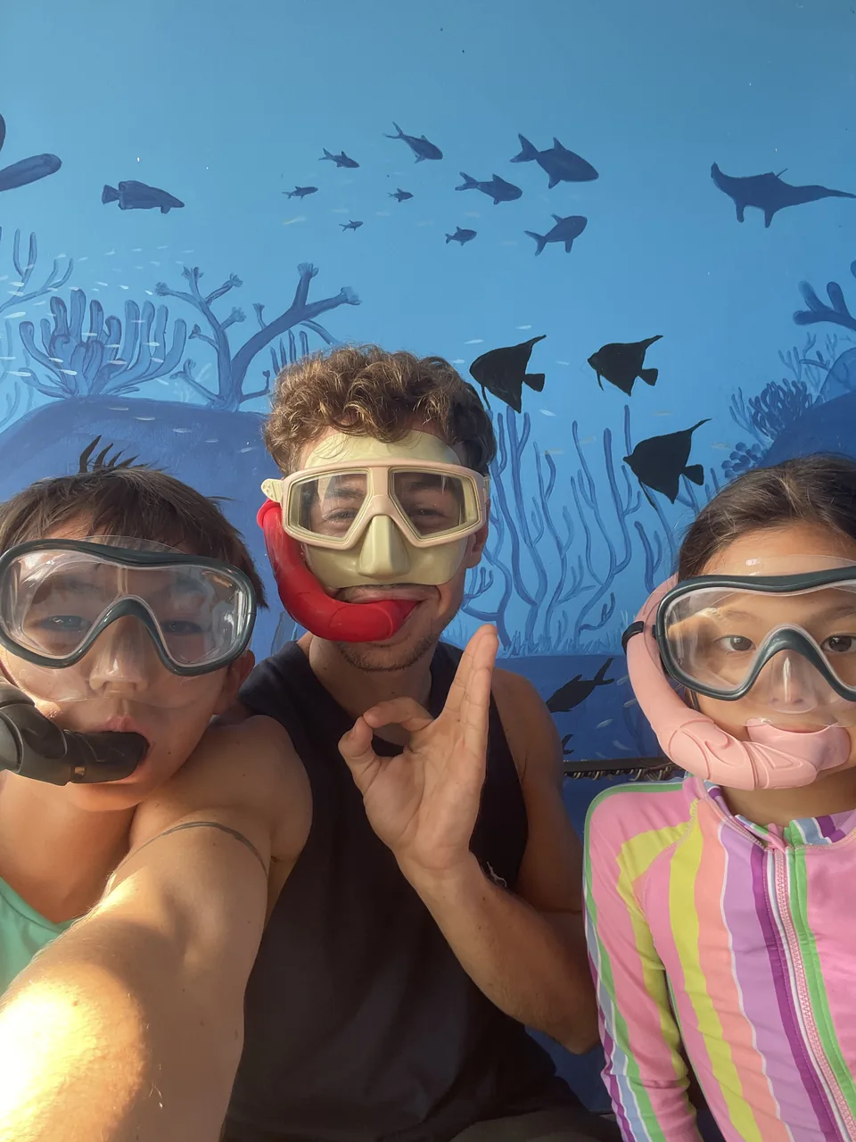 Two children and an instructor wearing masks and snorkels