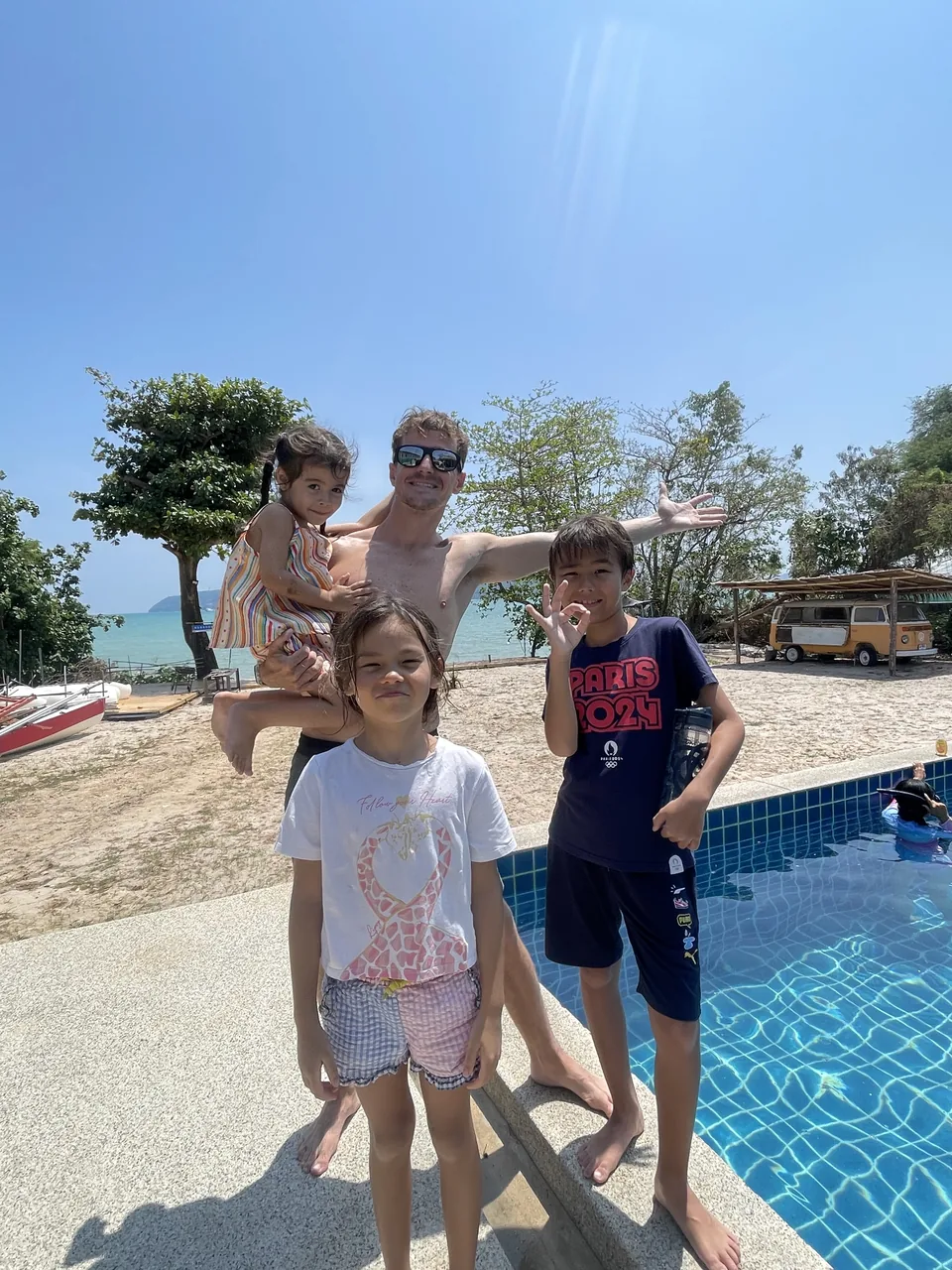An instructor and children gathered beside a pool near the beach