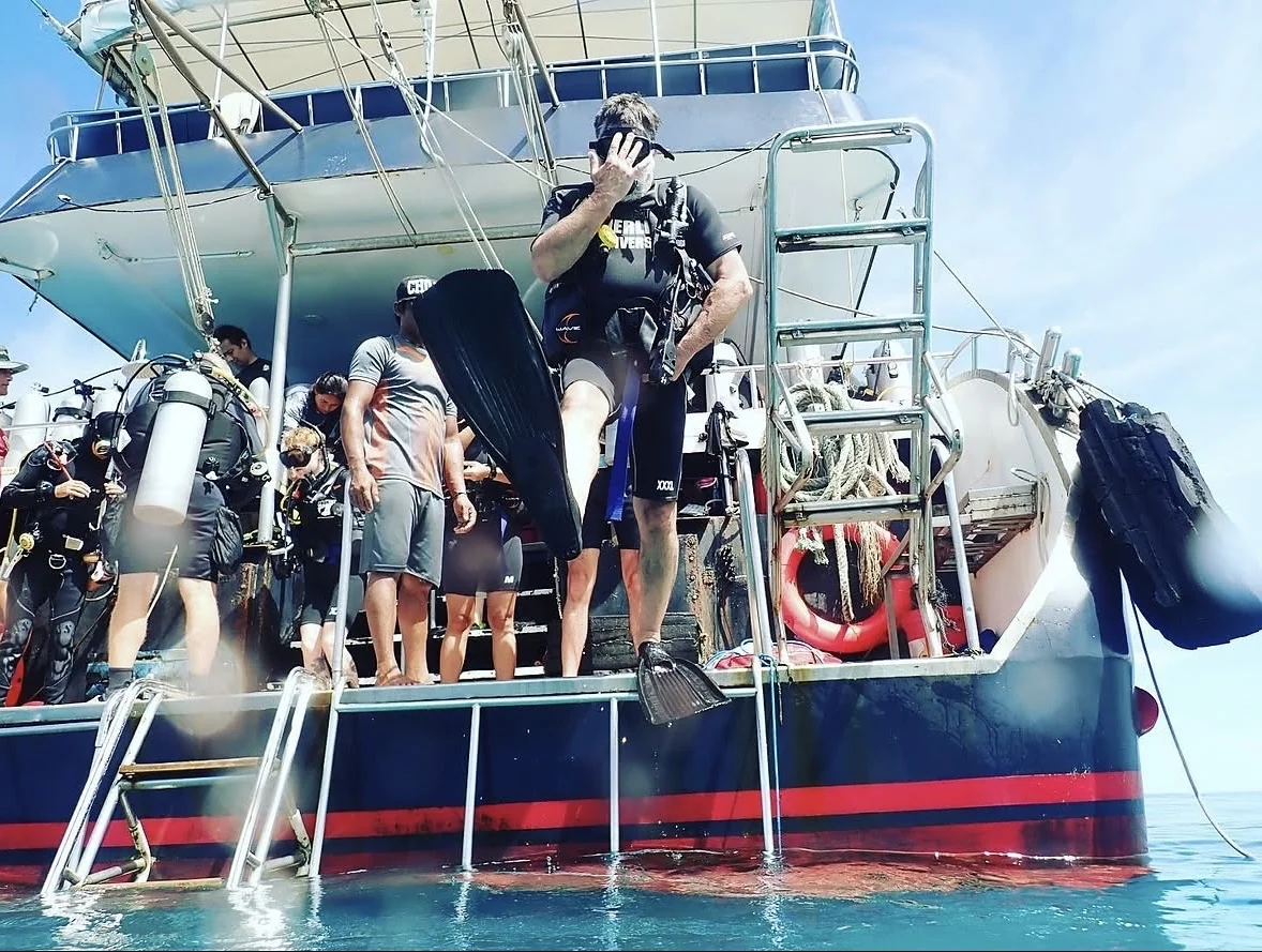 A scuba diver stepping from a dive boat into the sea