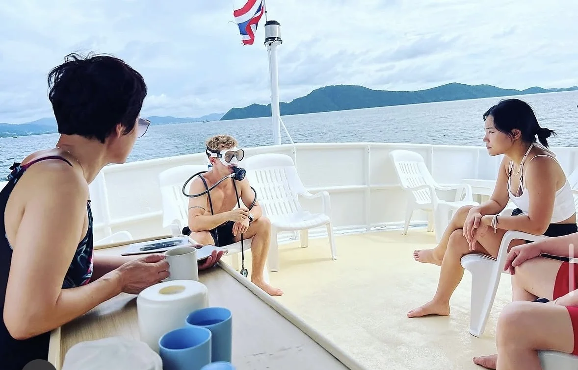 An instructor demonstrating scuba equipment to students aboard a boat