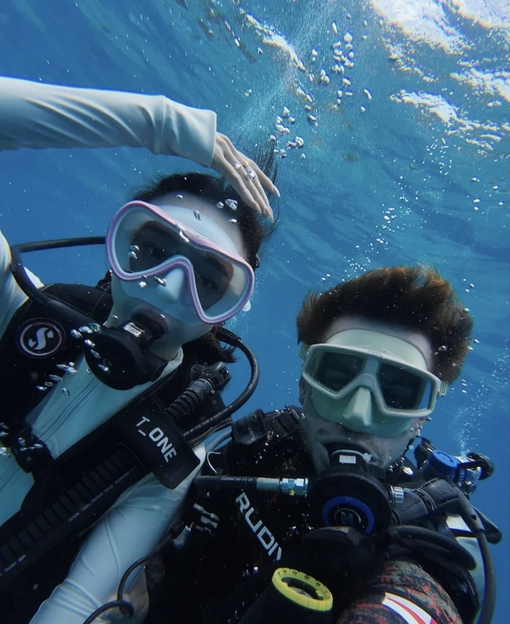 Two scuba divers underwater wearing masks and regulators